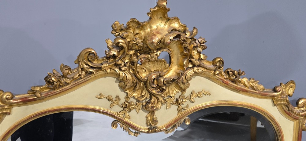 A large Victorian Rococo Revival giltwood and cream painted overmantel mirror featuring shell cresting, carved scrolls, and an arched glass plate. View IX
