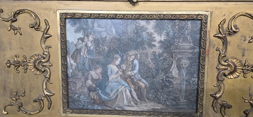 A tall gilded French trumeau mirror featuring a carved top pediment, an upper inset pastoral painting, and a rectangular mirror glass pane below. View IV