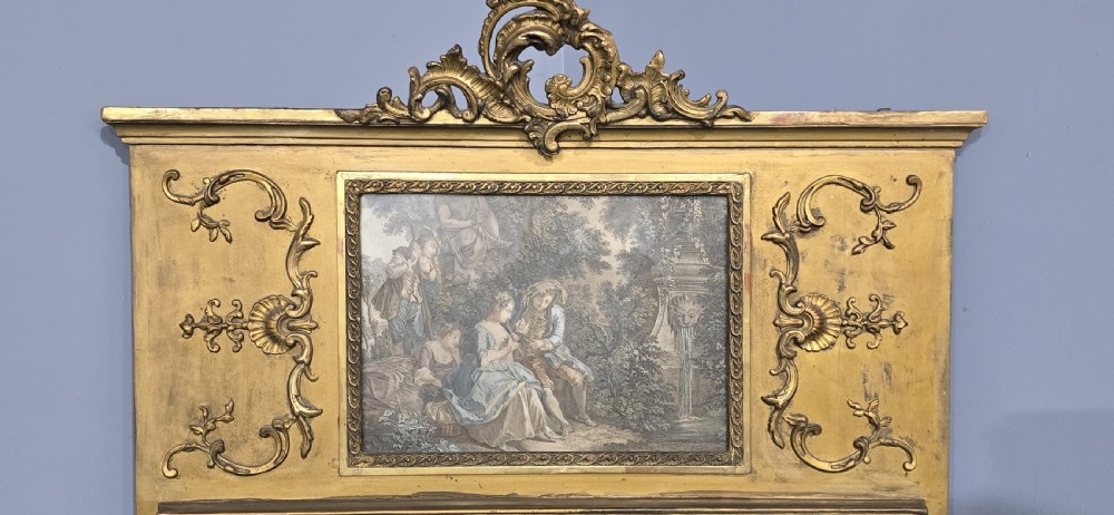 A tall gilded French trumeau mirror featuring a carved top pediment, an upper inset pastoral painting, and a rectangular mirror glass pane below. View V