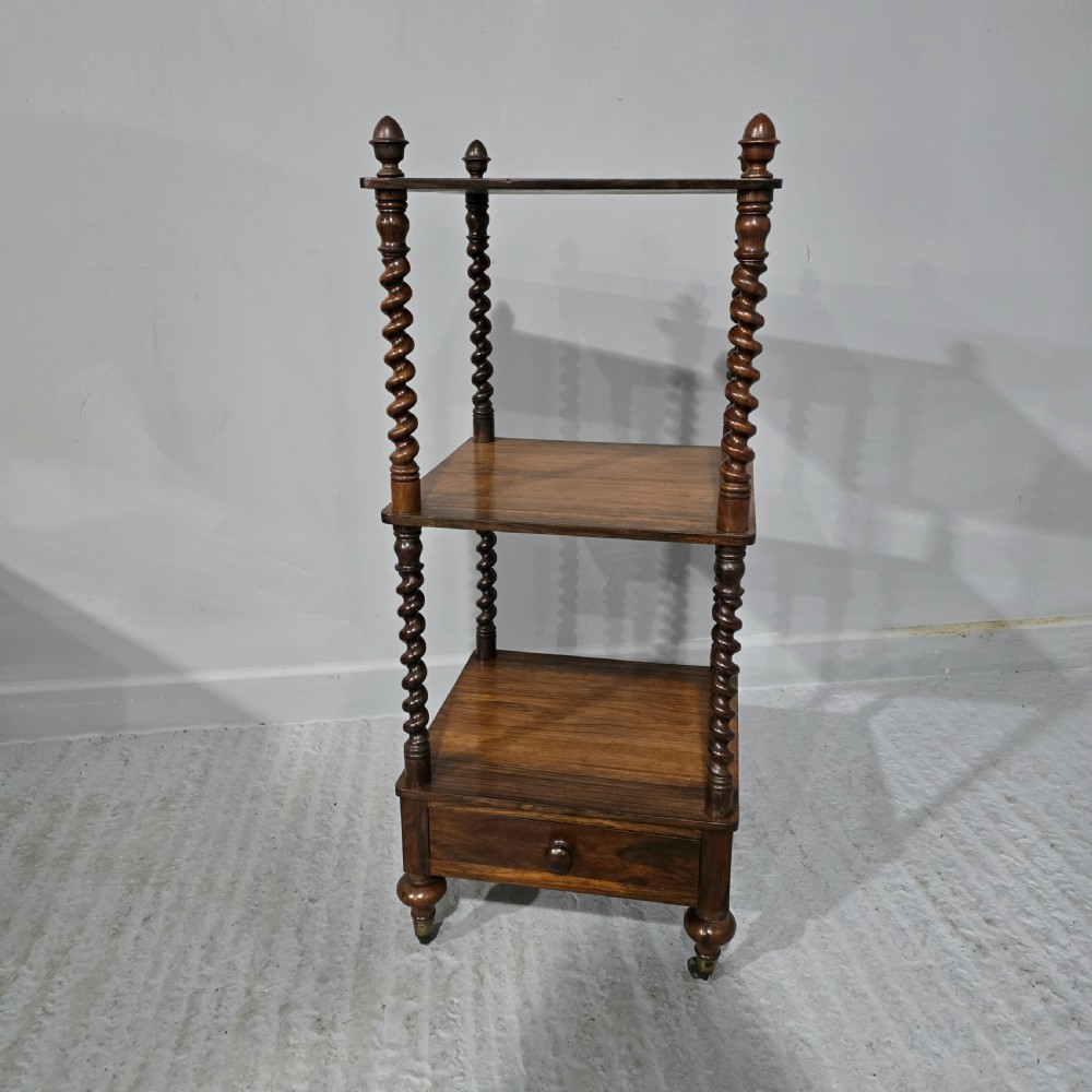 A three-tier William IV dark wood etagere featuring spiral twist uprights, top finials, a lower single drawer, and brass castors.