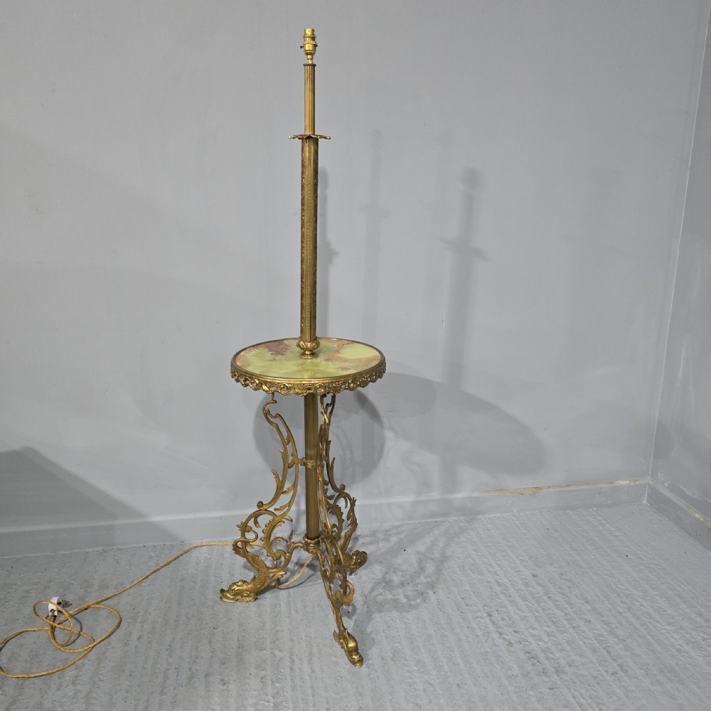 An antique cast brass standard lamp featuring an integrated circular green onyx tray and tripod scroll legs.