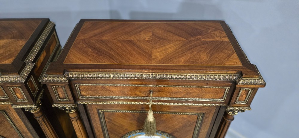 A pair of tall French Louis XVI style wooden side cabinets featuring parquetry veneers, fluted columns, gilt-bronze mounts, and central oval porcelain plaques painted with cherubs. View VI