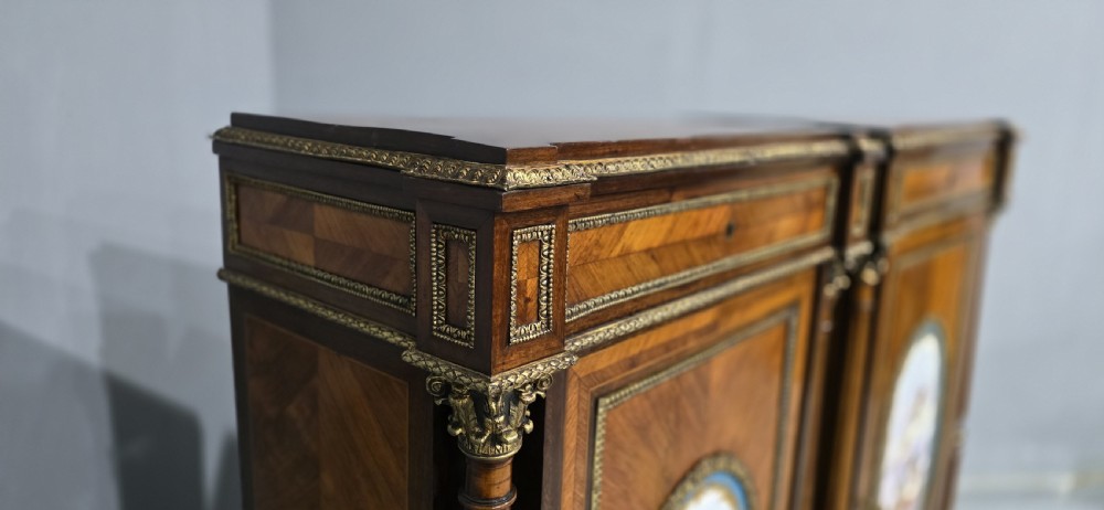 A pair of tall French Louis XVI style wooden side cabinets featuring parquetry veneers, fluted columns, gilt-bronze mounts, and central oval porcelain plaques painted with cherubs. View XVI