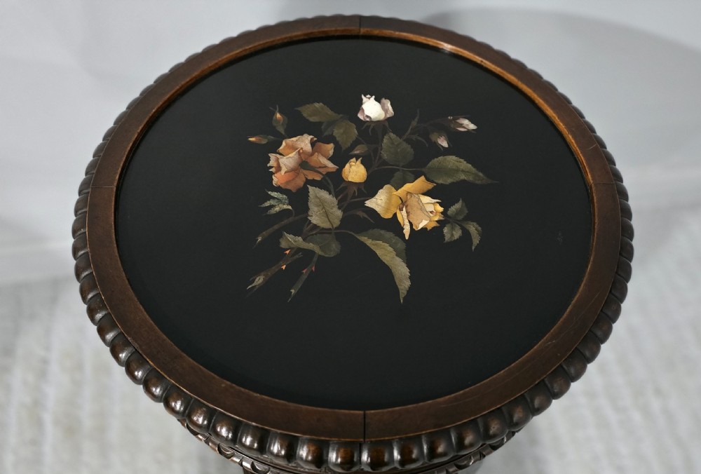 A Victorian dark carved timber side table with a circular black marble top featuring an inlaid floral pietra dura motif. View III