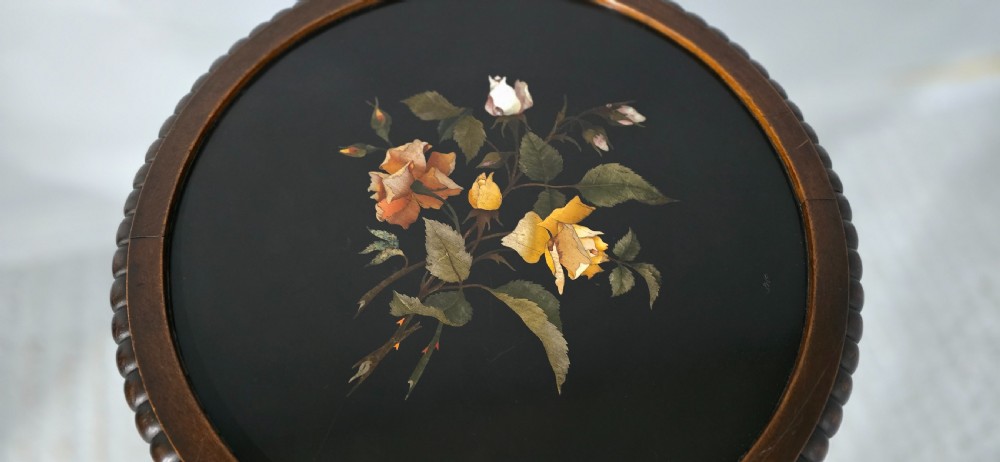 A Victorian dark carved timber side table with a circular black marble top featuring an inlaid floral pietra dura motif. View V