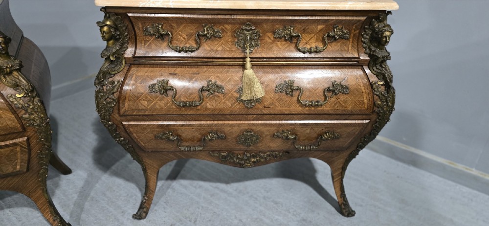 A pair of Louis XV style French bombe commodes featuring parquetry veneered drawer fronts, ornate metal mounts, and shaped marble tops. View VII