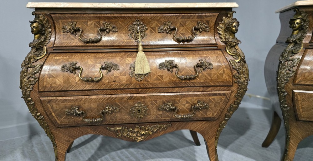 A pair of Louis XV style French bombe commodes featuring parquetry veneered drawer fronts, ornate metal mounts, and shaped marble tops. View XI
