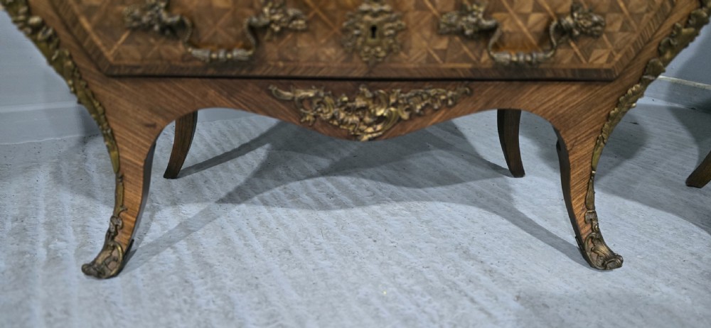A pair of Louis XV style French bombe commodes featuring parquetry veneered drawer fronts, ornate metal mounts, and shaped marble tops. View XII