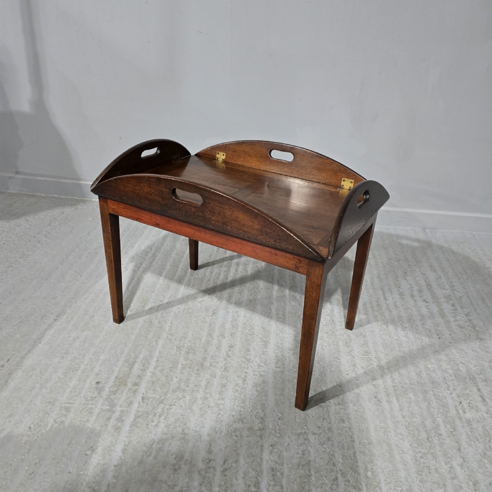 An oval Georgian mahogany butlers tray table featuring folding hinged sides with cutout handles on four straight legs. View II
