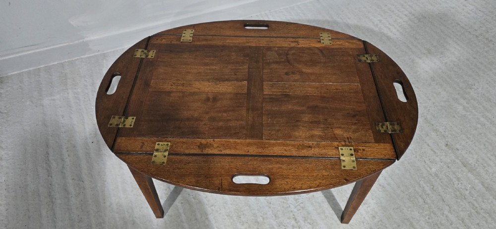 An oval Georgian mahogany butlers tray table featuring folding hinged sides with cutout handles on four straight legs. View III