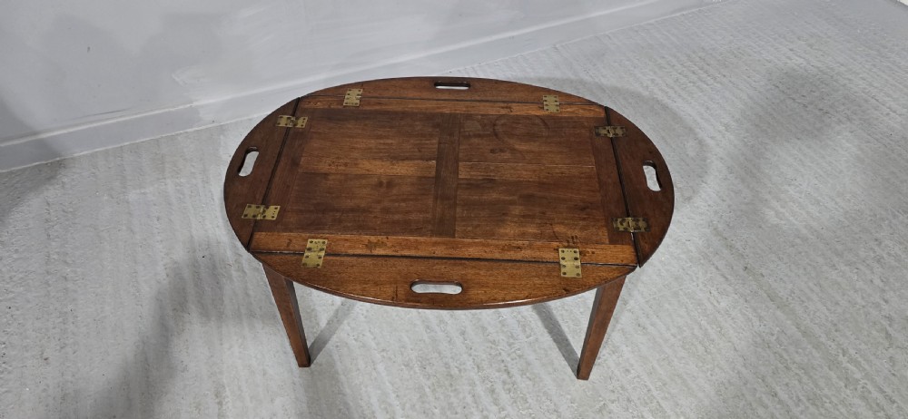 An oval Georgian mahogany butlers tray table featuring folding hinged sides with cutout handles on four straight legs. View IV