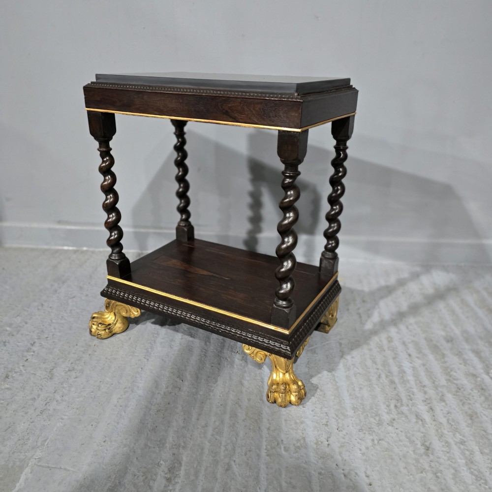 A rectangular dark rosewood two-tier side table featuring spiral turned legs, gilt borders, and carved gilded paw feet.