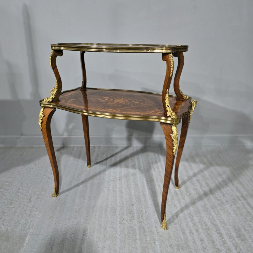 A two-tier French marquetry table featuring floral wood inlay, cabriole legs, and ornate gilt-bronze ormolu mounts.