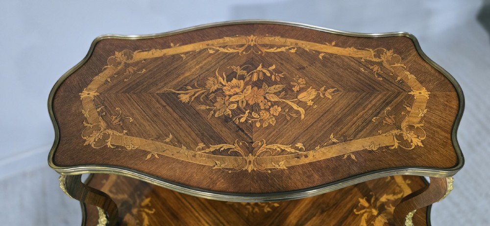 A two-tier French marquetry table featuring floral wood inlay, cabriole legs, and ornate gilt-bronze ormolu mounts. View V
