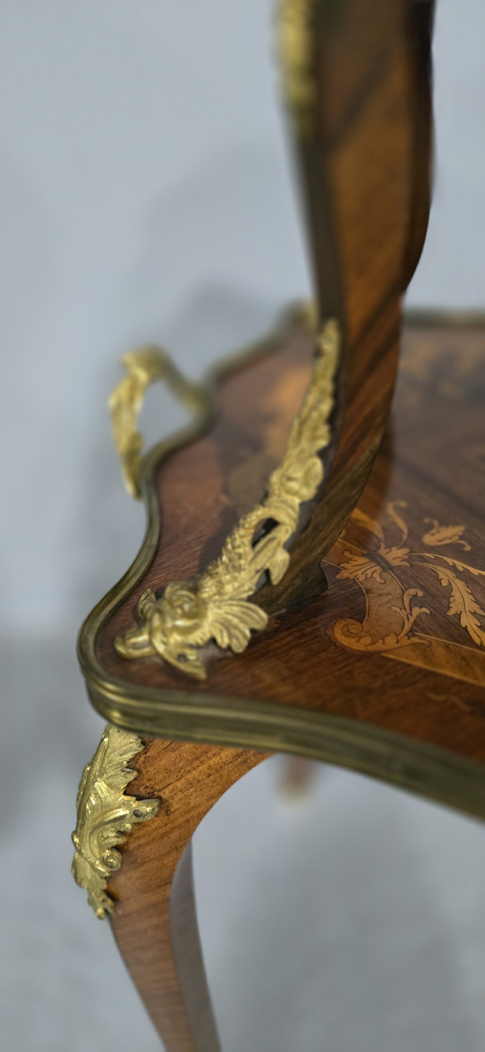 A two-tier French marquetry table featuring floral wood inlay, cabriole legs, and ornate gilt-bronze ormolu mounts. View IX