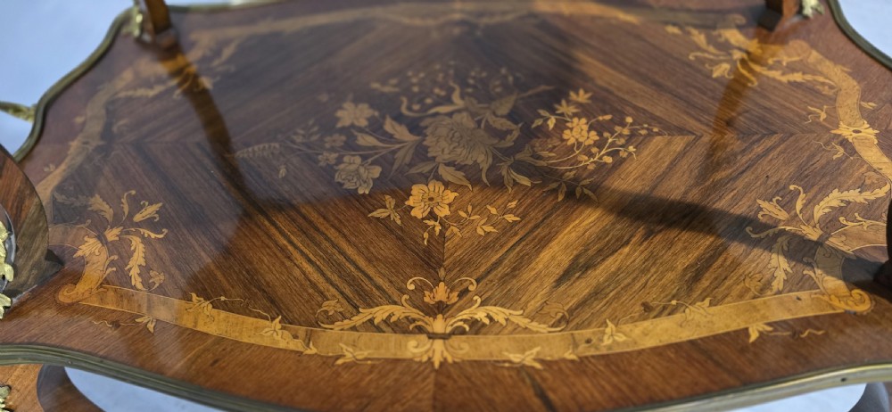 A two-tier French marquetry table featuring floral wood inlay, cabriole legs, and ornate gilt-bronze ormolu mounts. View XIV