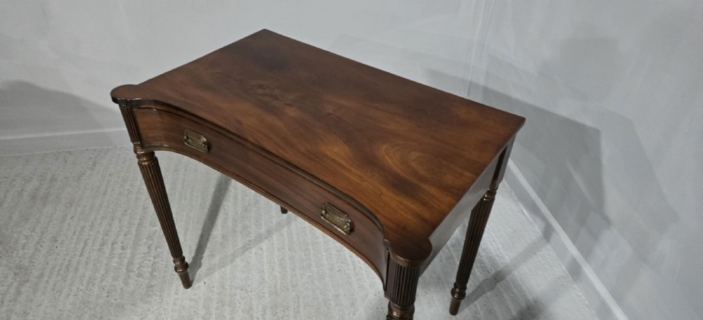 An antique Georgian mahogany side table featuring a single long drawer with brass handles and slender fluted tapered legs. View VII