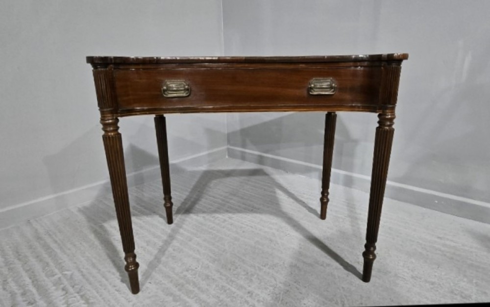An antique Georgian mahogany side table featuring a single long drawer with brass handles and slender fluted tapered legs. View XII