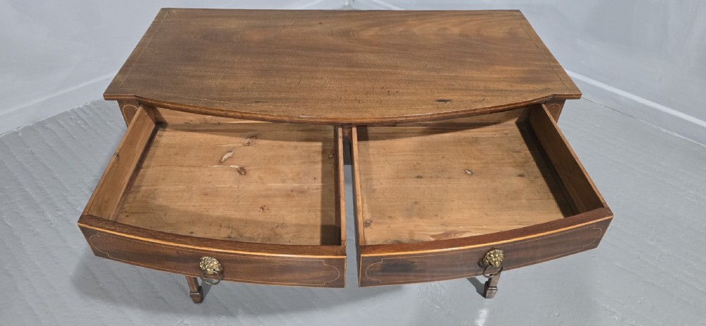 A Georgian mahogany bowfront side table featuring two string-inlaid drawers with lion mask brass handles, supported on square tapered legs. View VIII