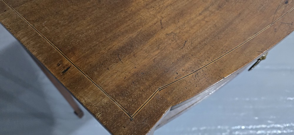 A Georgian mahogany bowfront side table featuring two string-inlaid drawers with lion mask brass handles, supported on square tapered legs. View XI