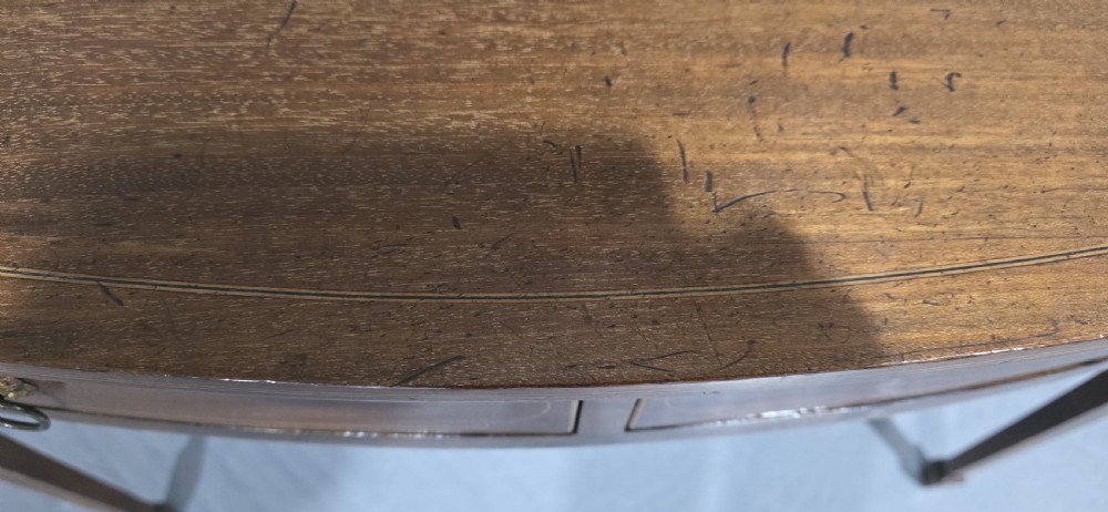 A Georgian mahogany bowfront side table featuring two string-inlaid drawers with lion mask brass handles, supported on square tapered legs. View XII
