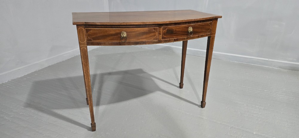 A Georgian mahogany bowfront side table featuring two string-inlaid drawers with lion mask brass handles, supported on square tapered legs. View XIV