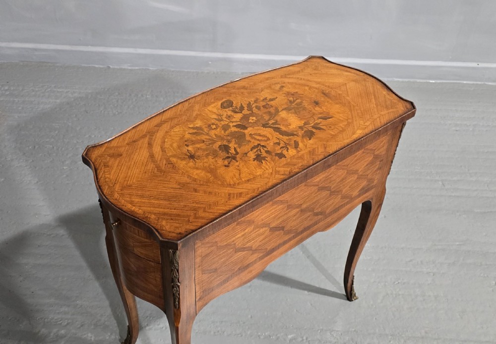 A French Louis XV style marquetry side table with a serpentine top, floral wood inlays, two drawers with brass handles, and slender cabriole legs. View XI