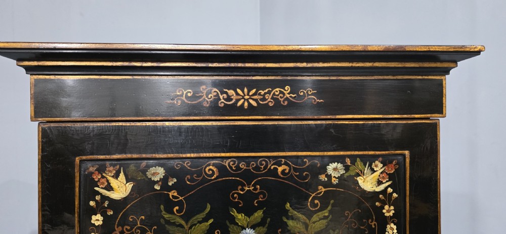 A tall black lacquered cabinet on stand featuring hand-painted floral urn artwork on the front door and curved stretchered legs. View III