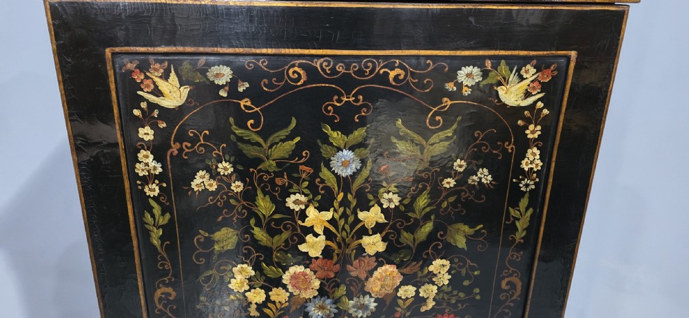 A tall black lacquered cabinet on stand featuring hand-painted floral urn artwork on the front door and curved stretchered legs. View XV