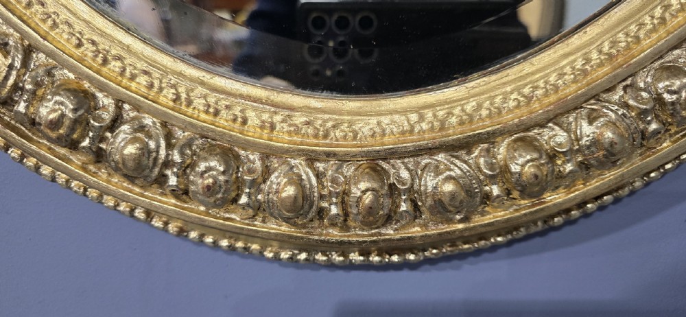 A Victorian oval wall mirror featuring a gilt gesso frame decorated with egg-and-dart moulding and a bevelled glass plate. View VIII