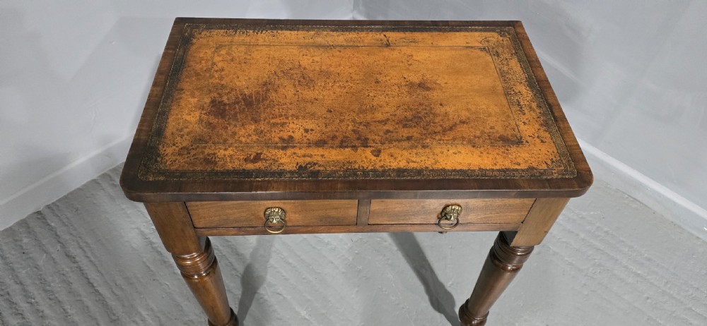 A small Victorian mahogany writing desk featuring a leather-inset top, two frieze drawers with brass lion-head ring handles, and turned legs on brass castors. View III