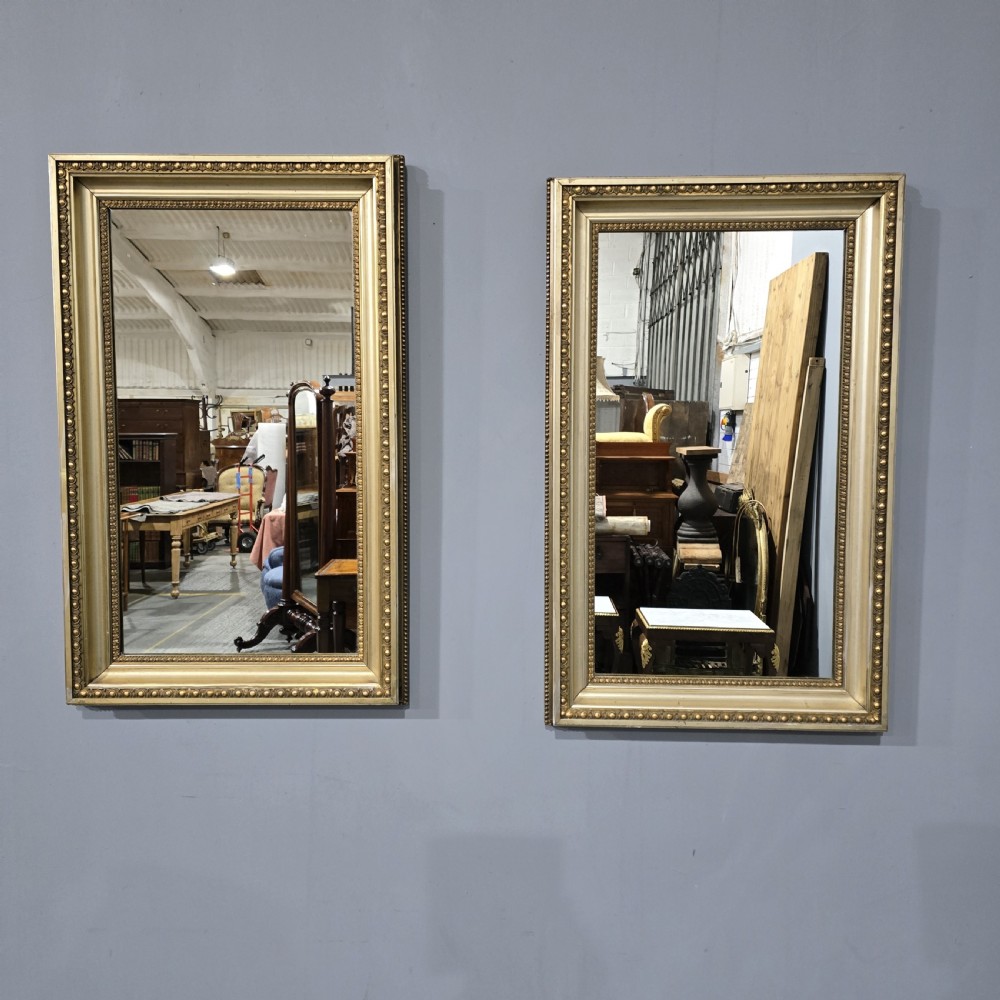 A matching pair of rectangular Victorian giltwood wall mirrors featuring beaded inner and outer frame details.