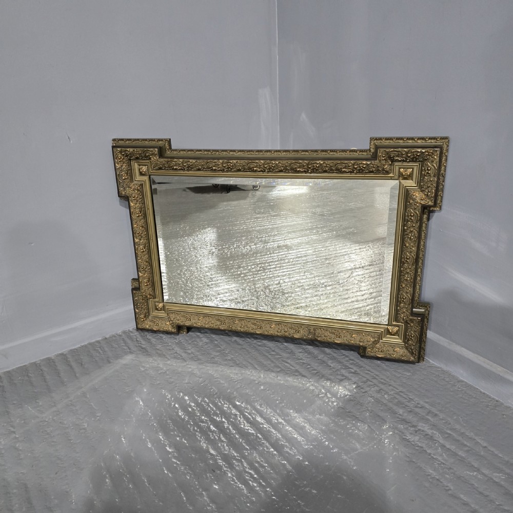 A large rectangular French giltwood wall mirror featuring elaborate carved corner mouldings and bevelled glass.