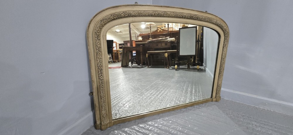 A Victorian arched overmantel mirror with a cream painted wooden frame detailed with floral relief moulding. View VII