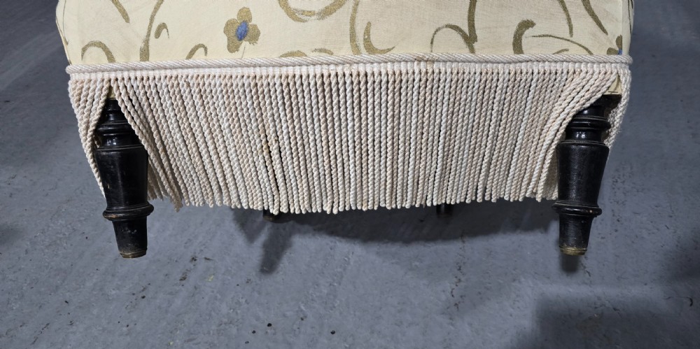 A pair of fully upholstered French Empire style armchairs covered in cream fabric with a green scroll pattern and deep tassel fringe skirting. View VI
