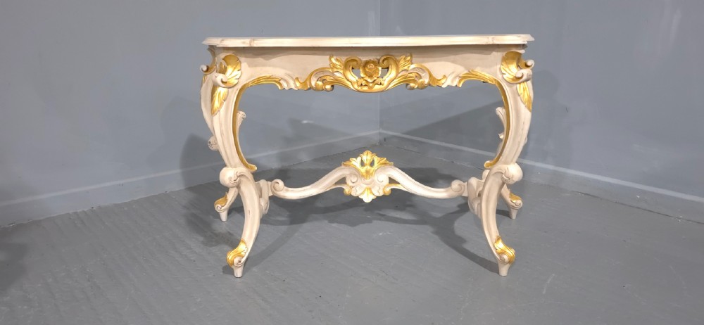 A French Rococo style console table featuring off-white painted wood, carved parcel-gilt details, cabriole legs, and a shaped stretcher base. View V