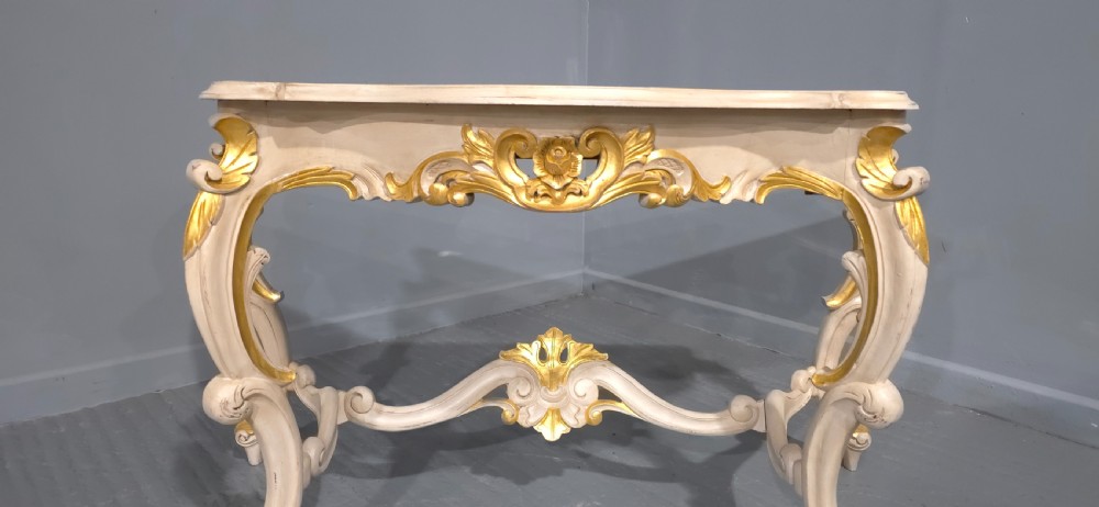 A French Rococo style console table featuring off-white painted wood, carved parcel-gilt details, cabriole legs, and a shaped stretcher base. View VI