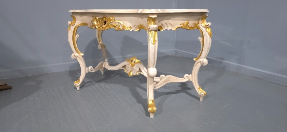 A French Rococo style console table featuring off-white painted wood, carved parcel-gilt details, cabriole legs, and a shaped stretcher base. View X