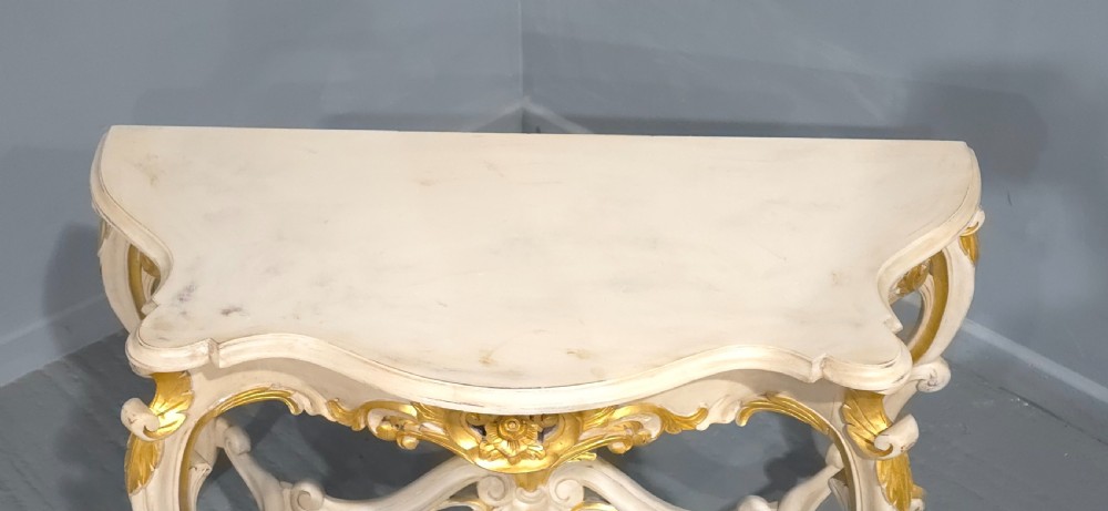 A French Rococo style console table featuring off-white painted wood, carved parcel-gilt details, cabriole legs, and a shaped stretcher base. View XII
