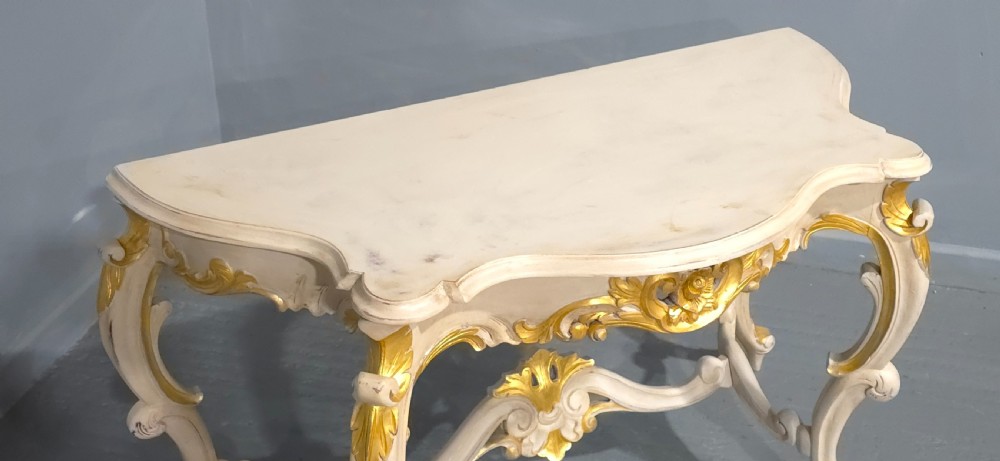 A French Rococo style console table featuring off-white painted wood, carved parcel-gilt details, cabriole legs, and a shaped stretcher base. View XIII