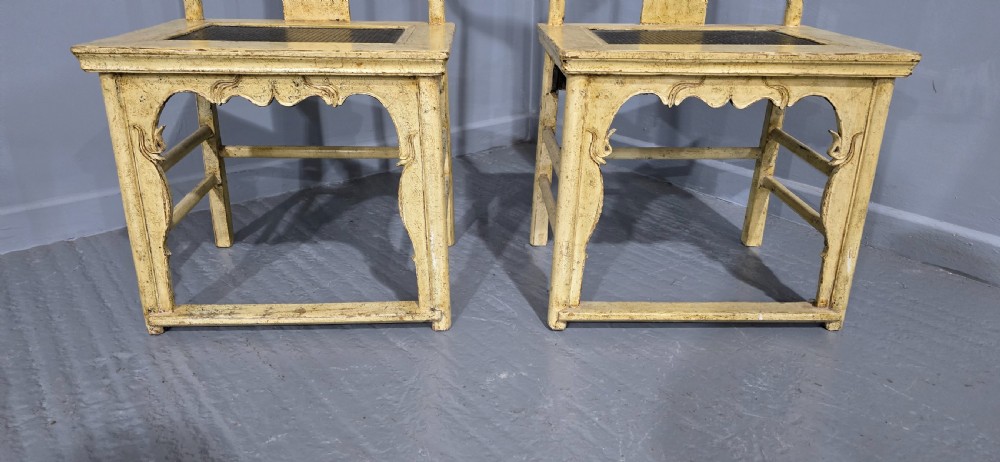 A pair of cream lacquered Chinese hall chairs featuring curved yoke crest rails, shaped splats, carved aprons, and dark inset seats. View II