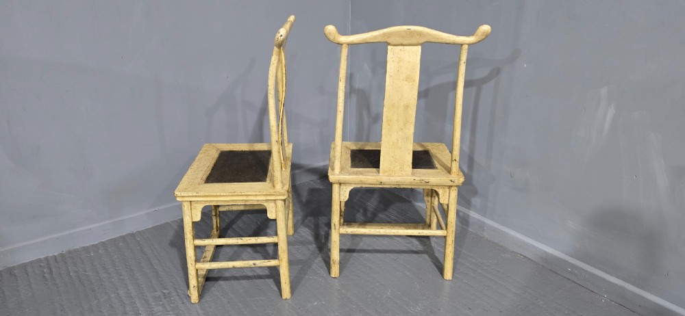A pair of cream lacquered Chinese hall chairs featuring curved yoke crest rails, shaped splats, carved aprons, and dark inset seats. View V