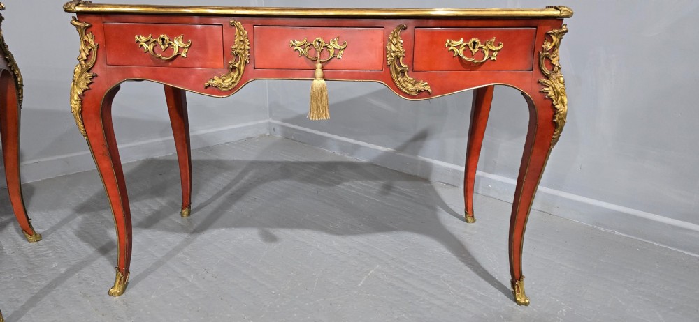 A pair of red lacquered French bureau plat writing desks featuring inset leather tops, three frieze drawers, and gilt bronze mounts on cabriole legs. View VI