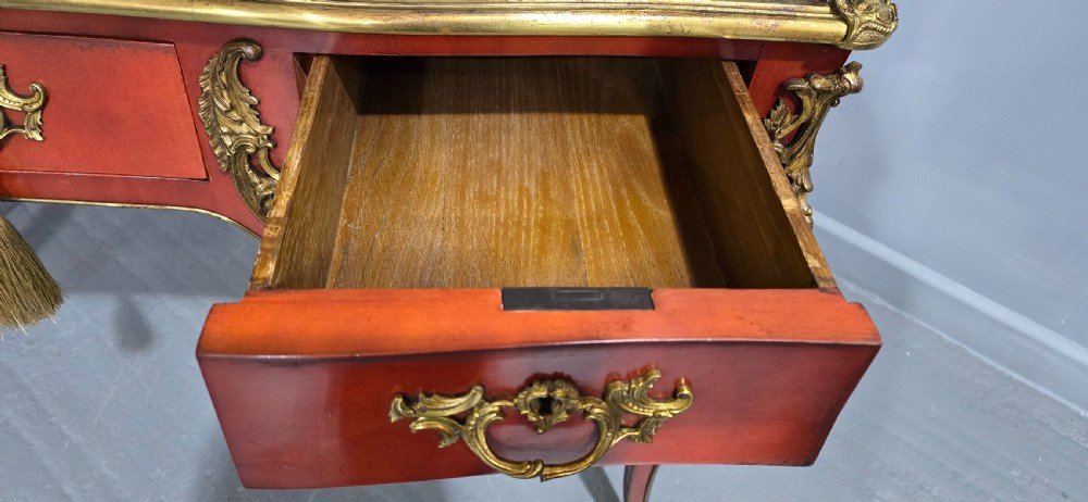 A pair of red lacquered French bureau plat writing desks featuring inset leather tops, three frieze drawers, and gilt bronze mounts on cabriole legs. View VII