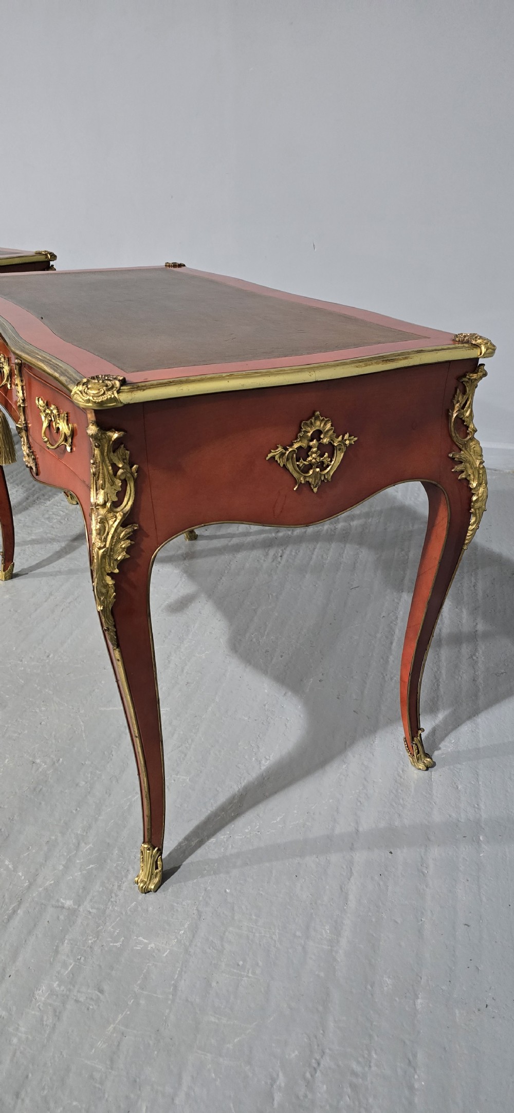 A pair of red lacquered French bureau plat writing desks featuring inset leather tops, three frieze drawers, and gilt bronze mounts on cabriole legs. View VIII