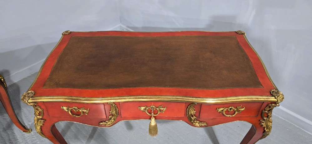A pair of red lacquered French bureau plat writing desks featuring inset leather tops, three frieze drawers, and gilt bronze mounts on cabriole legs. View IX
