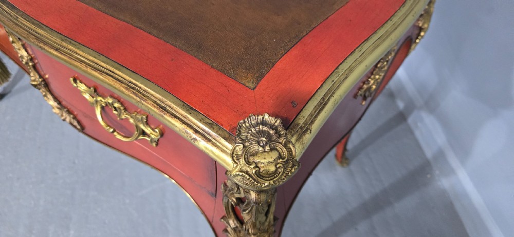 A pair of red lacquered French bureau plat writing desks featuring inset leather tops, three frieze drawers, and gilt bronze mounts on cabriole legs. View X