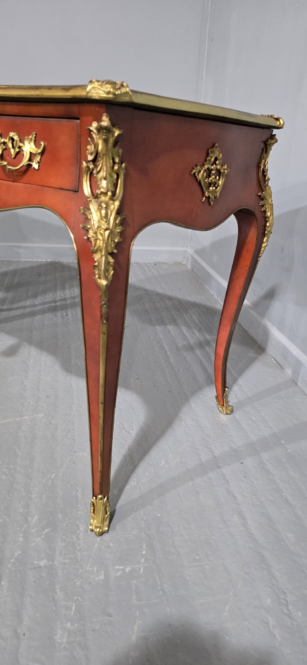 A pair of red lacquered French bureau plat writing desks featuring inset leather tops, three frieze drawers, and gilt bronze mounts on cabriole legs. View XII