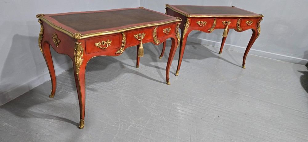 A pair of red lacquered French bureau plat writing desks featuring inset leather tops, three frieze drawers, and gilt bronze mounts on cabriole legs. View XVI