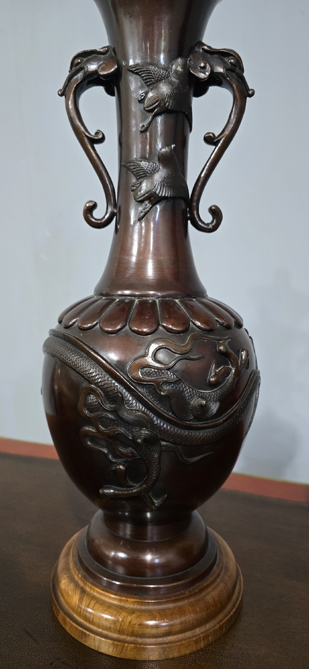 A pair of dark brown bronze urn-shaped table lamps featuring relief carvings of dragons and birds on turned wooden bases. View V